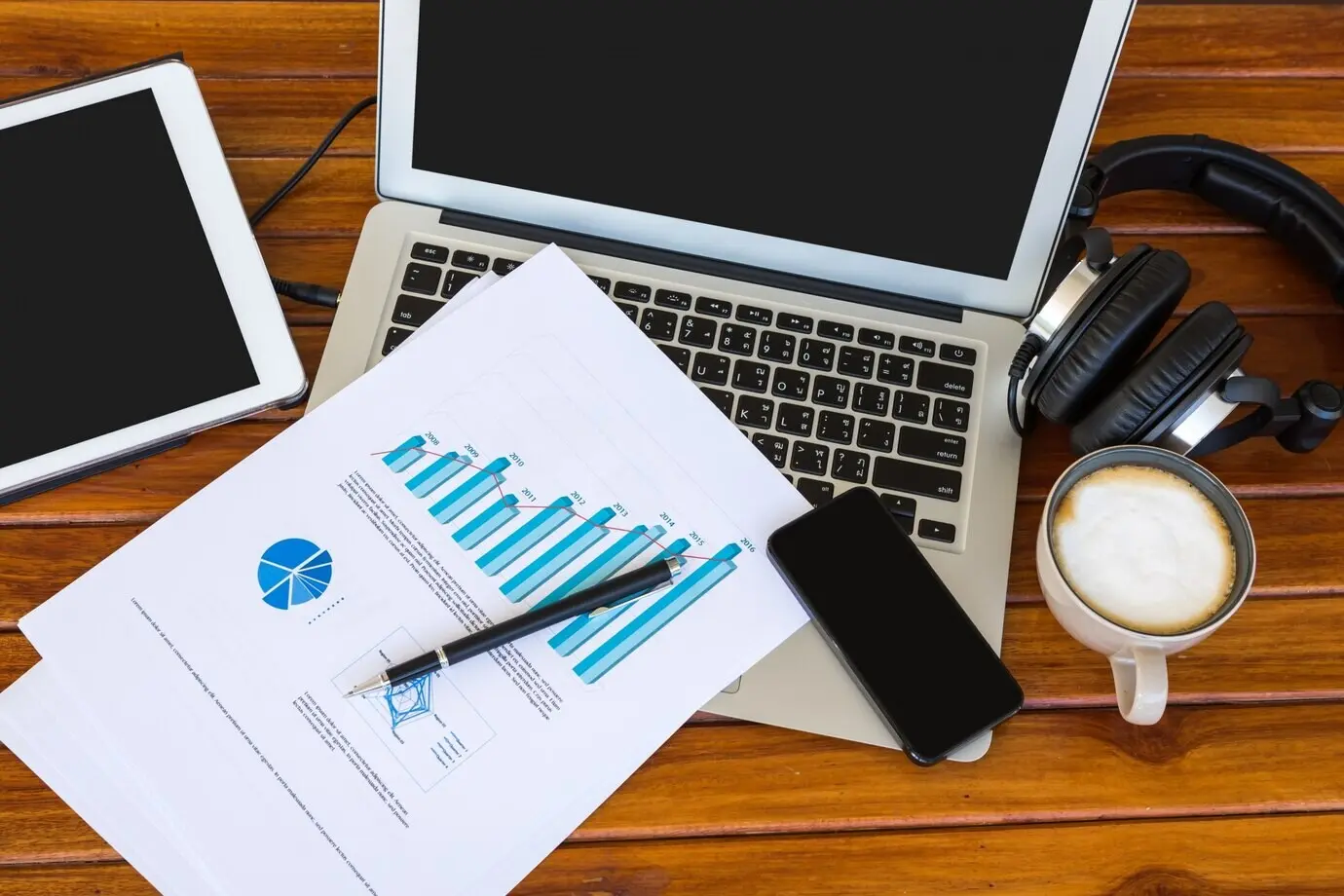 A laptop topped with papers featuring graphics.